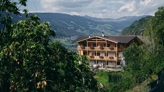 [Translate to Italiano:] Am Gschlunerhof, einem typischen Südtiroler Bergbauernhof, beschäftigt man sich mit Viehhaltung, Acker- und Obstanbau. Ruhesuchende können hier aber auch einen authentischen Urlaub am Bauernhof erleben. Umgeben von Wäldern und Wiesen konkurriert die Schönheit der Natur mit dem architektonischen Charme des Bauerngehöfts im traditionellen Stil. Die Natur und Althergebrachtes zu bewahren, ist den Besitzern ein großes Anliegen. Aus diesem Grund haben sie beim Um- und teilweise Neubau ihres Bauernhofs darauf geachtet, dass natürliche Rohstoffe und Materialien verwendet wurden. „Unser Haus wurde komplett aus Holz erbaut“, erzählt Arthur Mauroner voller Stolz. Alle Räume wurden mit Zirbenholz aus den umliegenden Wäldern ausgestattet. 